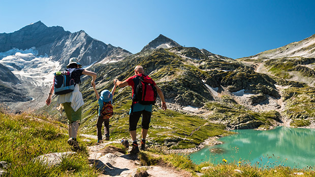 family with child hiking on holiday in austrian alps with lake a